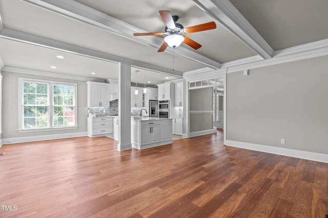 unfurnished living room with ceiling fan, hardwood / wood-style flooring, crown molding, and sink