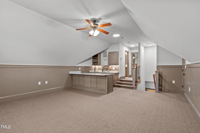 interior space featuring light carpet, wood walls, vaulted ceiling, and ceiling fan