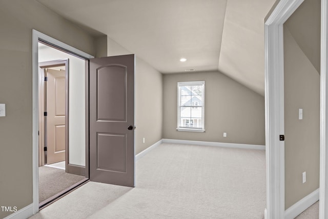 bonus room with vaulted ceiling and light colored carpet