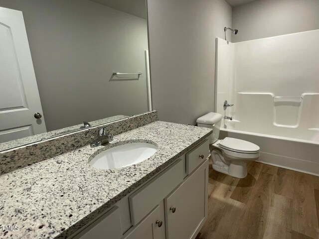 full bathroom with  shower combination, vanity, toilet, and hardwood / wood-style flooring