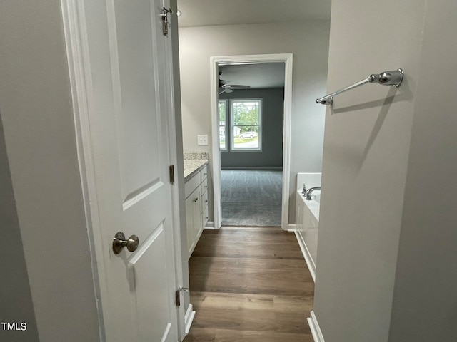 bathroom with ceiling fan, vanity, hardwood / wood-style flooring, and a tub