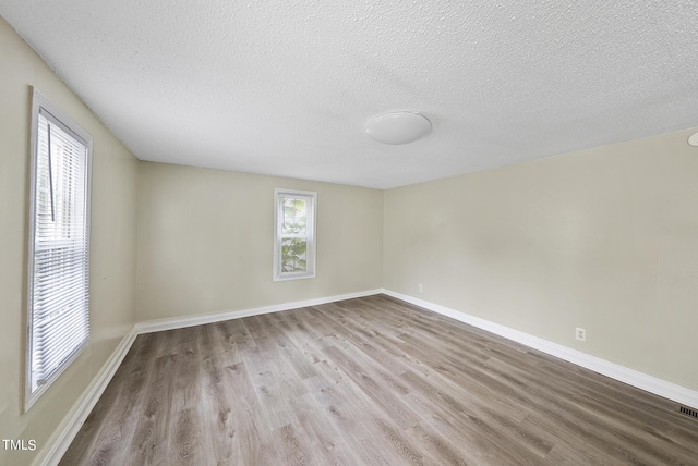 spare room with baseboards, wood finished floors, and a textured ceiling
