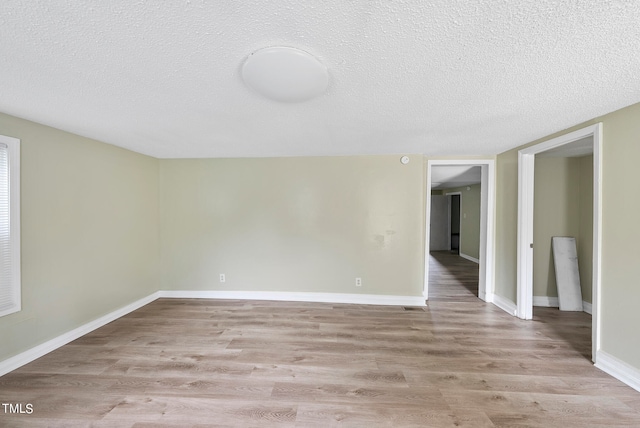 empty room with light wood-type flooring and a textured ceiling