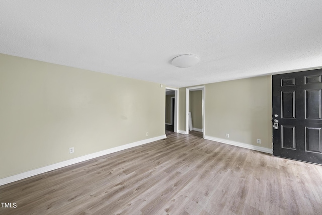 spare room featuring wood finished floors, a textured ceiling, and baseboards