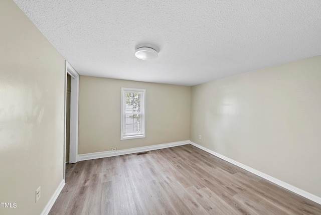 spare room with a textured ceiling and light hardwood / wood-style floors