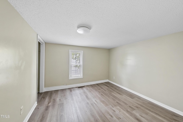 empty room with baseboards, wood finished floors, and a textured ceiling