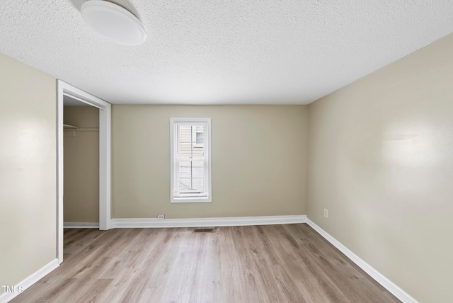 unfurnished bedroom with a textured ceiling, light hardwood / wood-style flooring, and a closet