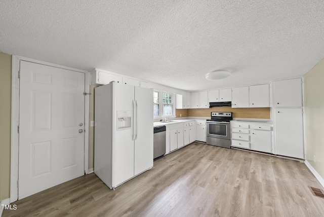 kitchen featuring light wood finished floors, stainless steel appliances, under cabinet range hood, and a textured ceiling