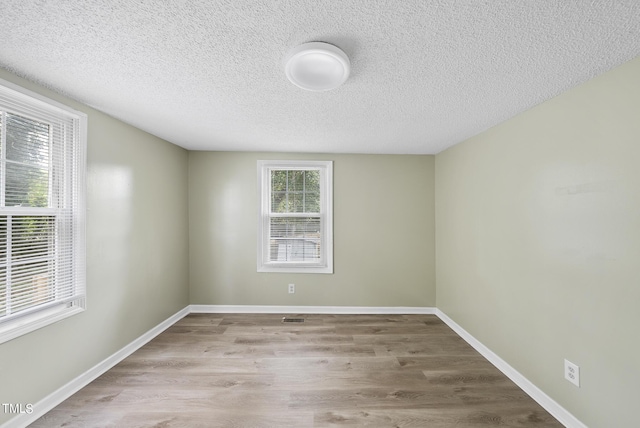 spare room featuring baseboards, wood finished floors, and a textured ceiling