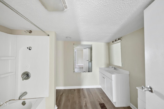 bathroom with wood-type flooring, a textured ceiling, shower / tub combination, and vanity