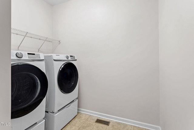 laundry area featuring light tile patterned flooring and washing machine and clothes dryer