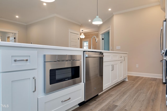 kitchen featuring white cabinetry, decorative light fixtures, light hardwood / wood-style flooring, ornamental molding, and wall oven