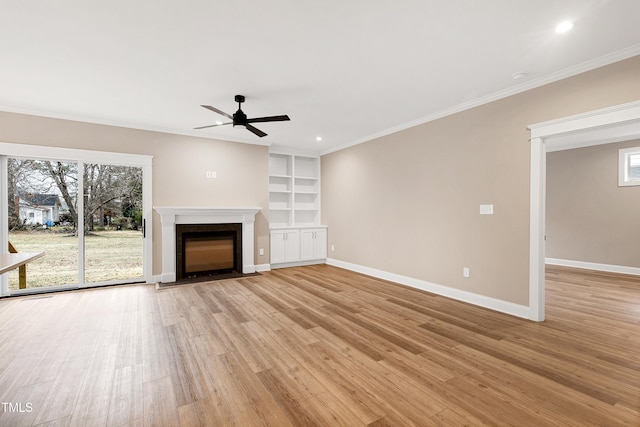 unfurnished living room featuring light hardwood / wood-style flooring, crown molding, a wealth of natural light, and built in shelves