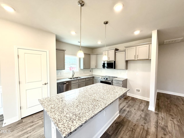 kitchen with gray cabinets, a sink, dark wood finished floors, a center island, and stainless steel appliances