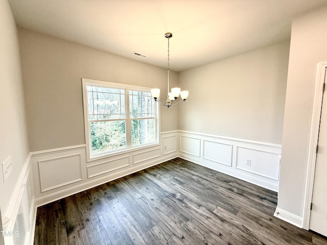 unfurnished dining area with dark wood finished floors, visible vents, and an inviting chandelier