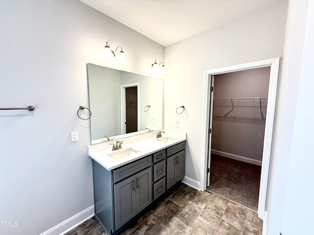 full bath featuring double vanity, a spacious closet, baseboards, and a sink