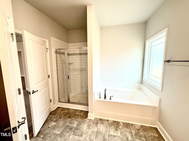 bathroom with baseboards, a bath, and a shower stall