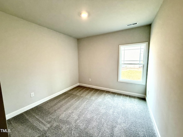 unfurnished room featuring dark colored carpet, visible vents, and baseboards