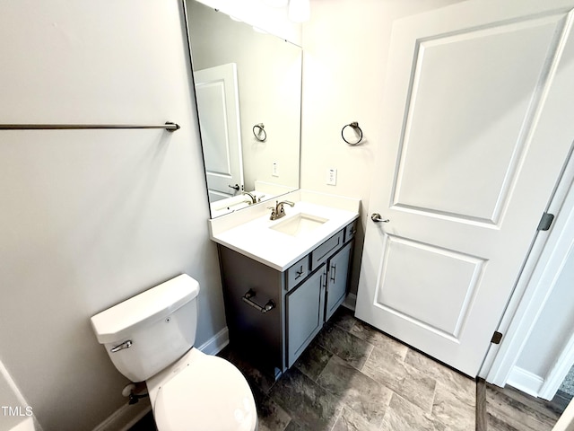 half bath with vanity, toilet, and baseboards