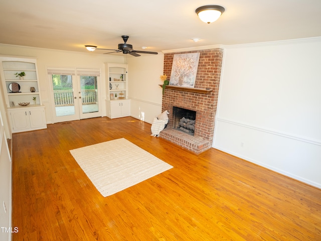 unfurnished living room with hardwood / wood-style floors, ceiling fan, crown molding, and a brick fireplace