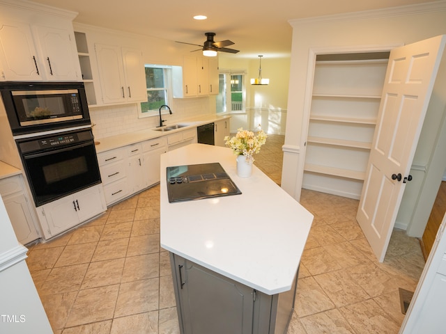 kitchen with black appliances, a kitchen island, decorative light fixtures, sink, and white cabinets