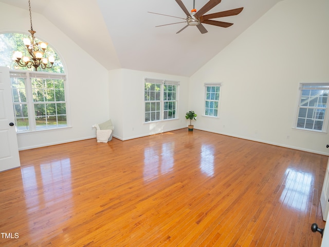 unfurnished living room with high vaulted ceiling, light wood-type flooring, a wealth of natural light, and ceiling fan with notable chandelier