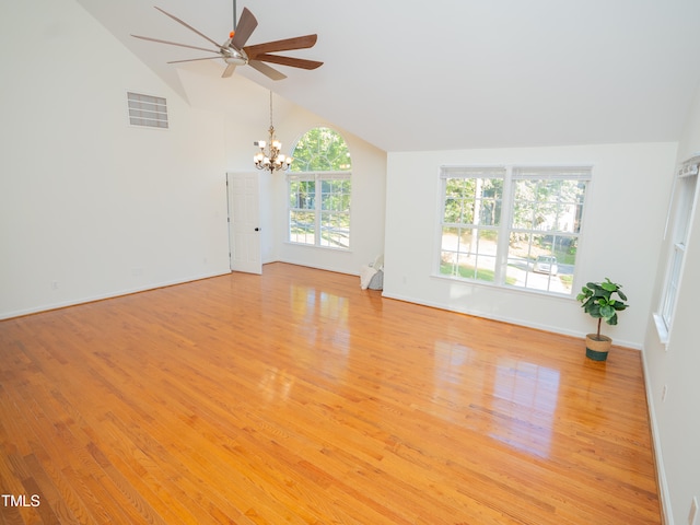 unfurnished living room featuring a wealth of natural light, ceiling fan with notable chandelier, light wood-type flooring, and lofted ceiling