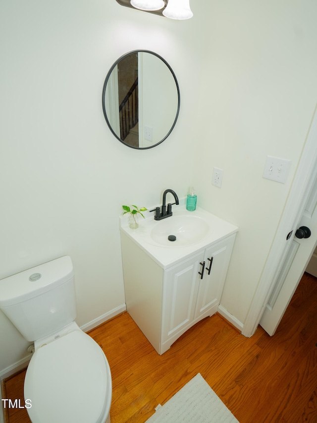 bathroom with wood-type flooring, toilet, and vanity