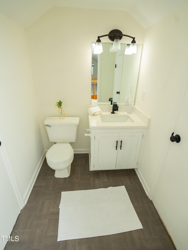 bathroom with toilet, vanity, and vaulted ceiling