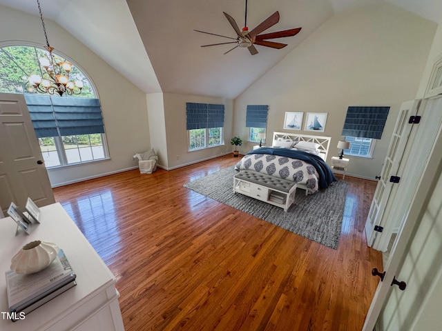 bedroom featuring hardwood / wood-style floors, ceiling fan with notable chandelier, multiple windows, and high vaulted ceiling