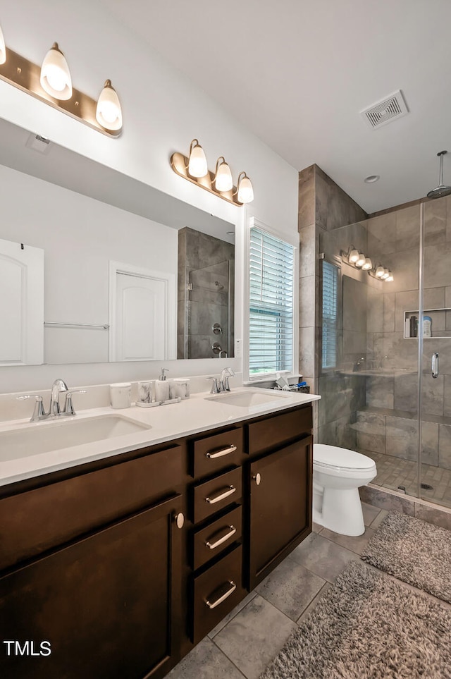 bathroom featuring tile patterned flooring, a shower with shower door, vanity, and toilet