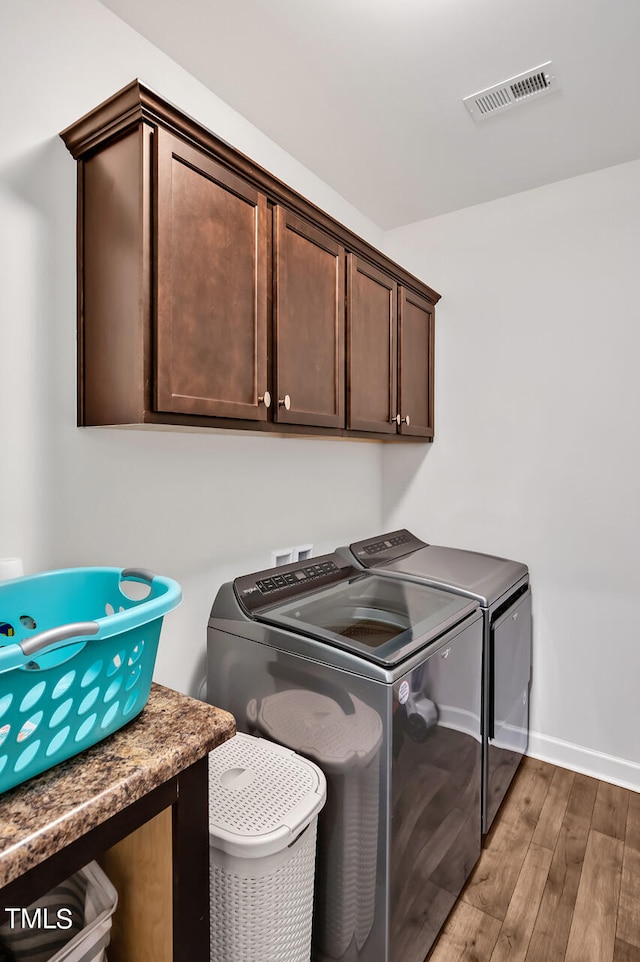 laundry room featuring washer and clothes dryer, cabinets, and dark hardwood / wood-style flooring