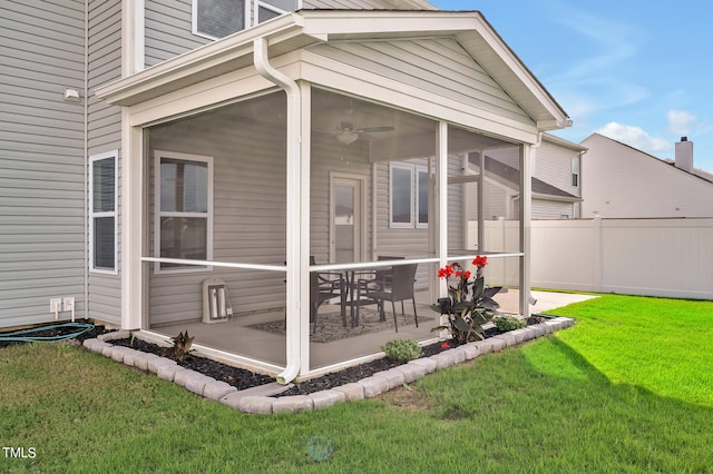 view of side of home featuring ceiling fan, a sunroom, a lawn, and a patio