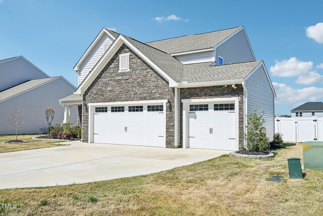 view of side of home with stone siding, concrete driveway, a gate, and an attached garage