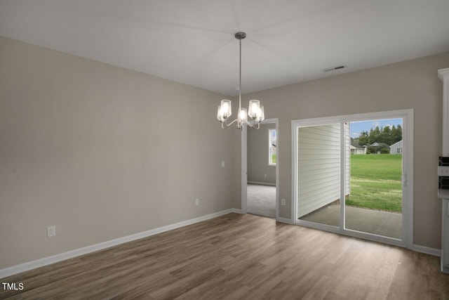 unfurnished dining area with wood finished floors, a chandelier, and baseboards