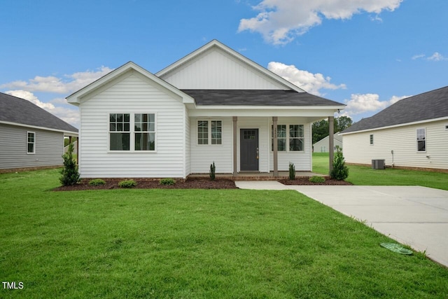 view of front of property featuring a front yard, central air condition unit, covered porch, a shingled roof, and board and batten siding