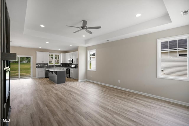 kitchen with white cabinets, a kitchen island, stainless steel appliances, a breakfast bar, and light hardwood / wood-style floors