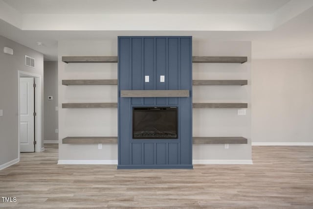 unfurnished living room featuring wood finished floors, baseboards, and a large fireplace