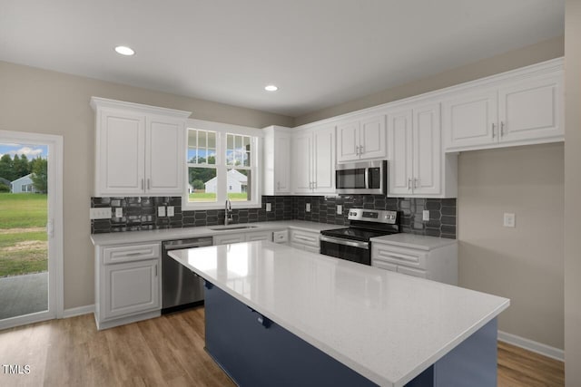 kitchen featuring stainless steel appliances, a sink, tasteful backsplash, white cabinetry, and recessed lighting