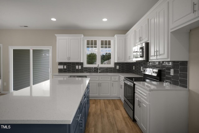 kitchen featuring stainless steel appliances, a sink, white cabinetry, and recessed lighting