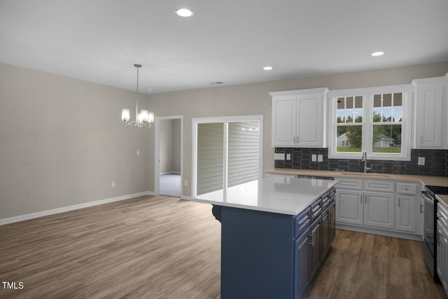 kitchen featuring a sink, blue cabinetry, white cabinetry, a chandelier, and recessed lighting