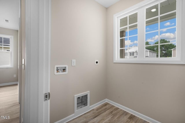 laundry room with electric dryer hookup, hookup for a washing machine, wood finished floors, and baseboards