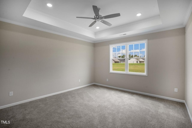 carpeted empty room with a tray ceiling, a ceiling fan, recessed lighting, ornamental molding, and baseboards