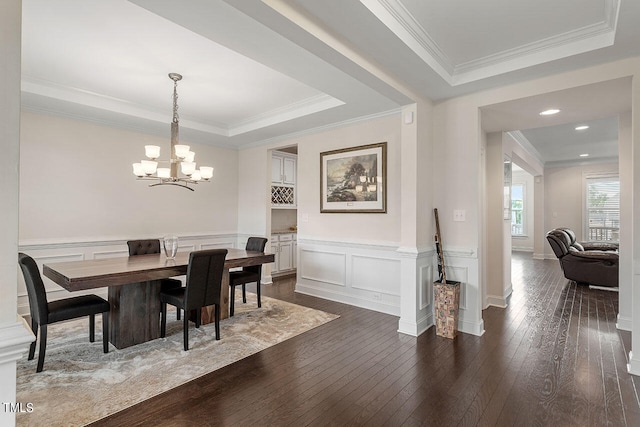 dining room featuring a notable chandelier, a raised ceiling, crown molding, and dark wood-type flooring