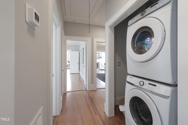 washroom featuring wood-type flooring and stacked washing maching and dryer