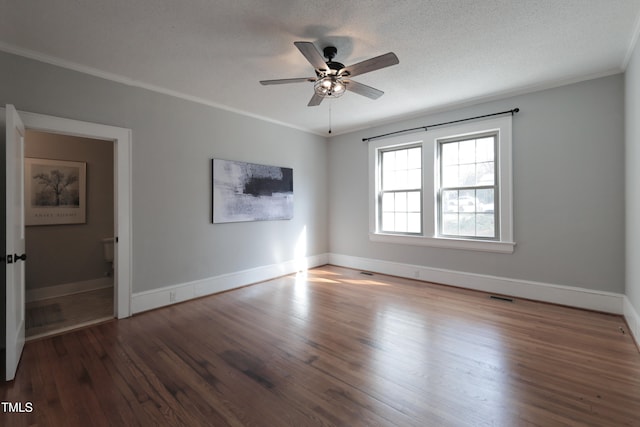 empty room with a textured ceiling, ornamental molding, and dark hardwood / wood-style floors