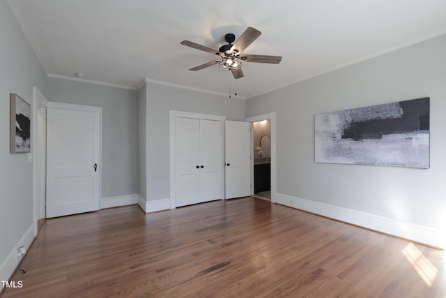 unfurnished bedroom featuring dark wood-type flooring, ceiling fan, a closet, and crown molding