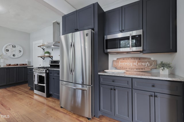 kitchen with island range hood, appliances with stainless steel finishes, light stone counters, and light wood-type flooring