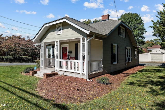 bungalow-style home featuring an outdoor structure, a garage, a front lawn, and covered porch