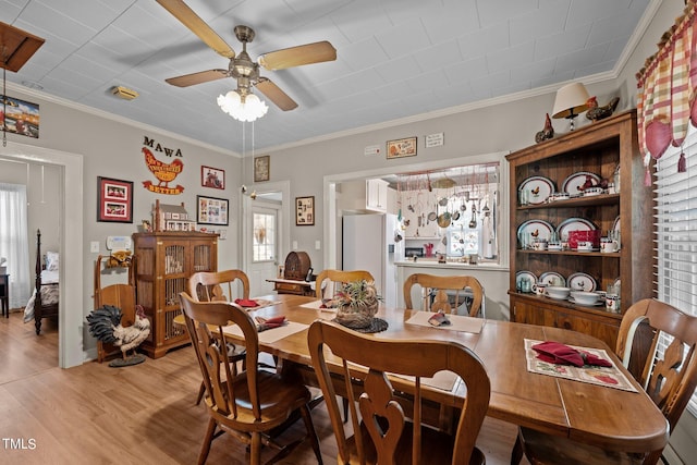 dining space featuring ornamental molding, light wood-type flooring, and ceiling fan